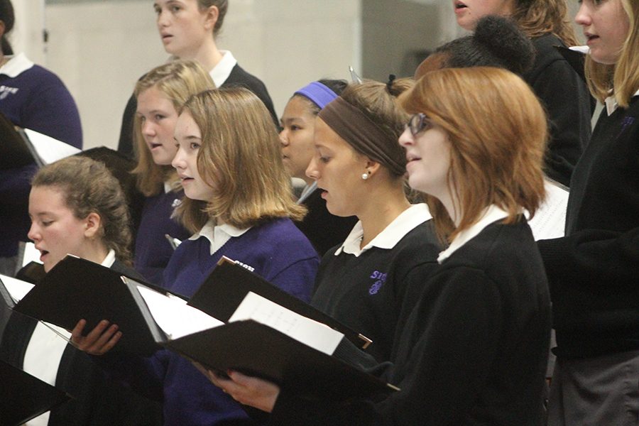 Seniors Anna Oliphant and Madeline Dercher sing during mass with choir.