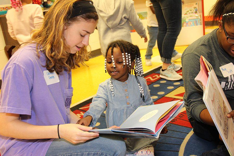 Freshman Caitlin Gura reads to a young girl at the Upper Room.