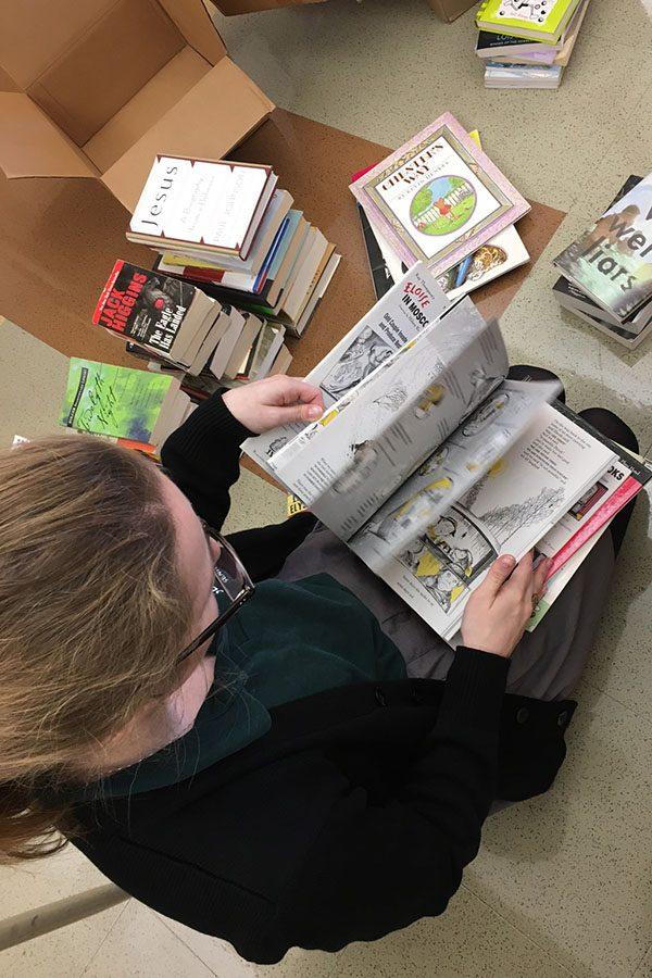 Senior book club member Grace Prusa sorts through  the donations that will be given to the Upper Room and Journey House.