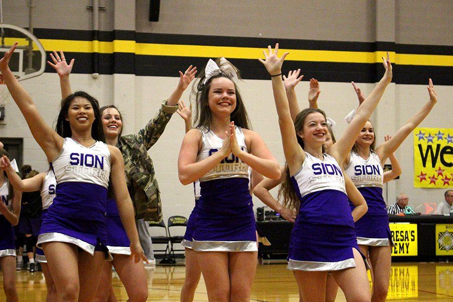 Cheer team members junior Courtney Hiatt, and sophomores Liz Oltjen and Savannah Childress wave to the crowd at the end of their performance.