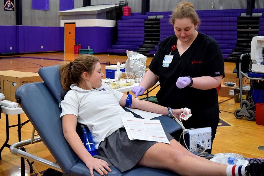 Junior Bailey Runchey watches as a nurse cleans her arm in preparation to donate blood.