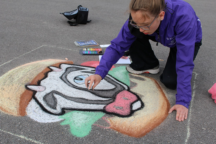 Junior Emma Cosner adds the final touches to her Earth Day themed chalk drawing piece. 
