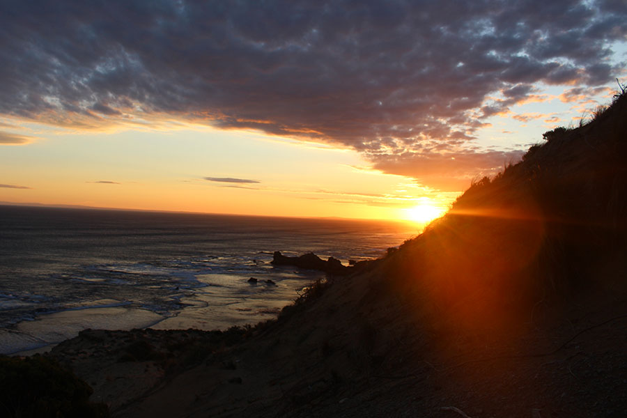 The sun sinks behind the cliffs of Sorrento beach.