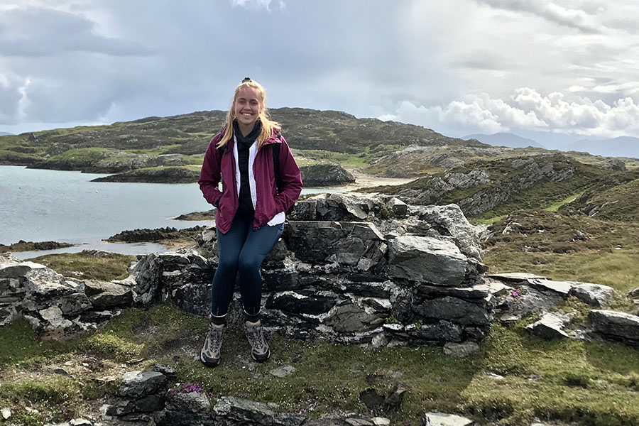 Posing for a picture, senior Olivia Dopheide sits atop a rock overlooking the ocean. 