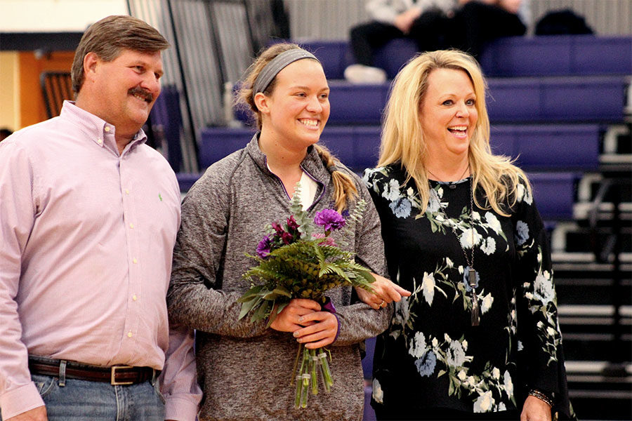 During volleyball senior night, senior Caroline Mollerus walks with her parents after receiving flowers from underclassmen Oct.11. 