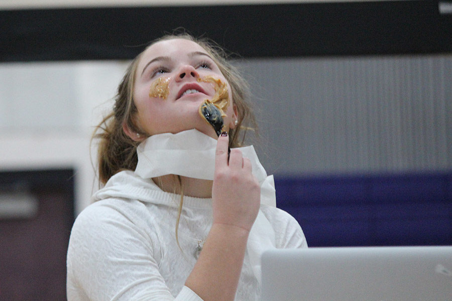 Sophomore Molly O’Keefe spreads peanut butter with a spoon as a face mask during the sophomore Food For Thought skit.