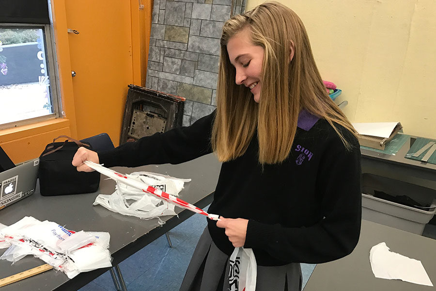 Junior Kelsey Wilcoxson laughs as she ties two plastic bag strips together to be rolled up into a ball.