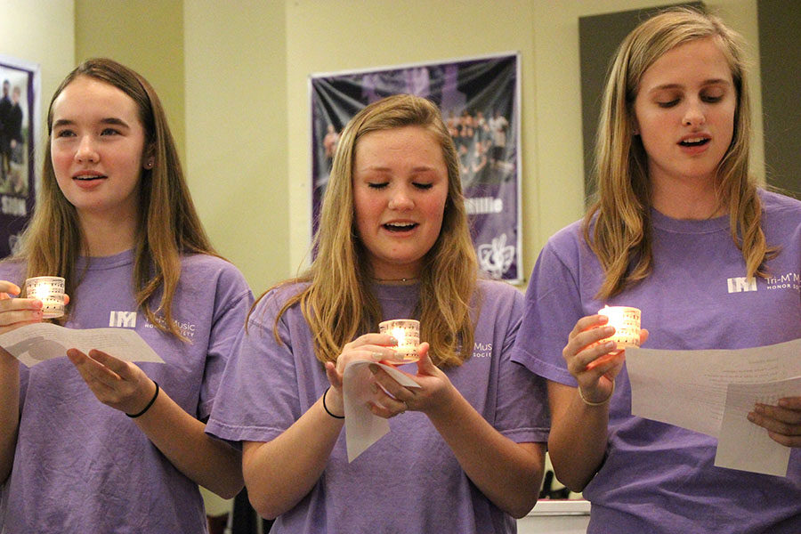 Sophomores Peyton Wade, Avery Kuhls and Emma Hutchin hold candles while performing a song at the Tri-M recital Nov. 14.