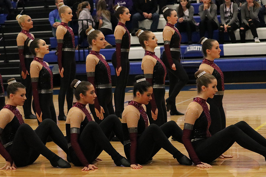 The dance team prepares for their music to begin to start their high kick routine.