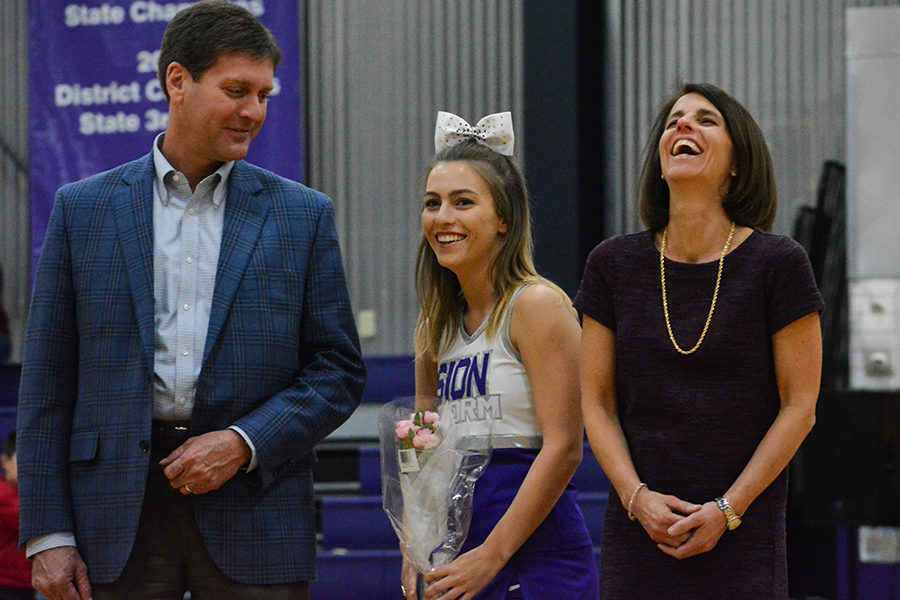 Cheer senior Catherine Wilkerson laughs alongside her parents while her plans after high school are announced over the speaker at dance and cheer senior night Jan. 23.