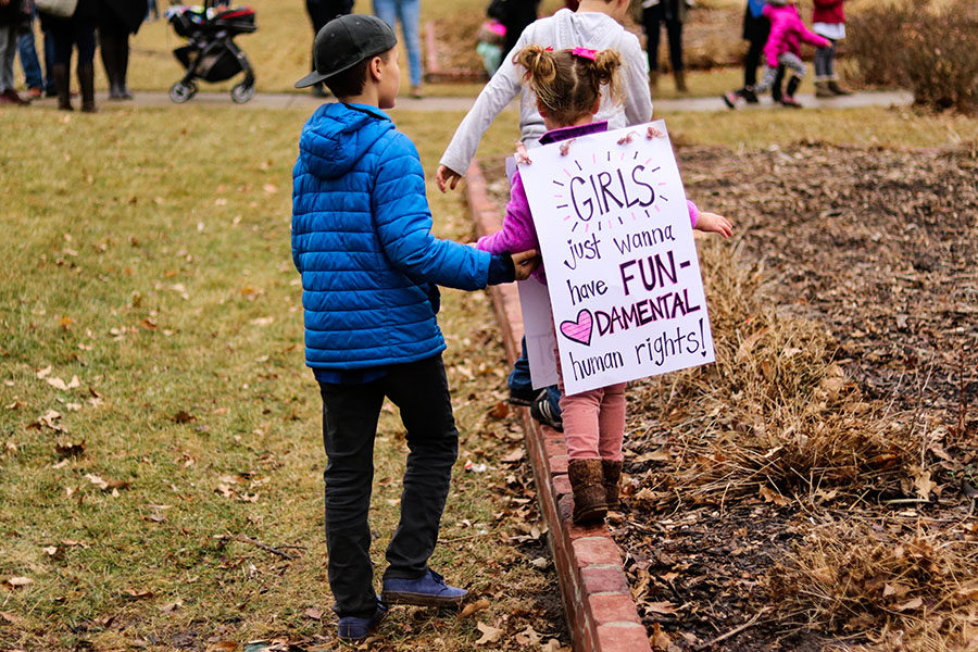 A little girl walks on brick while holding her holder brother's hand at the Women's March in Lawrence, Kansas Jan. 20. 