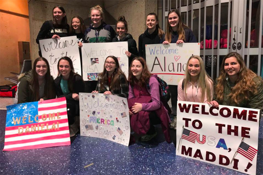 The Australian exchange students pose for a picture with their host sisters holding welcome sings.