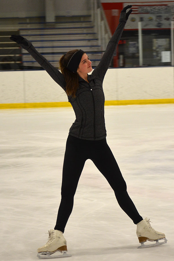 While at her morning practice, junior Maggie Carr extends her arms above her head to stick the landing of a lutz. 