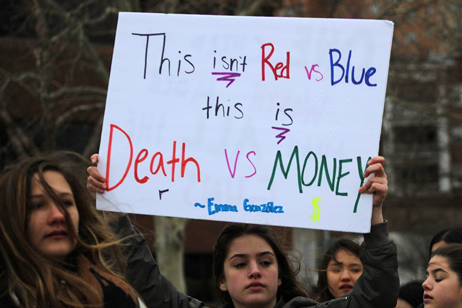 Girl holds her sign above her head as she marches down Emmanuel Cleaver II Blvd for March For Our Lives in Kansas City, MO on March 24.