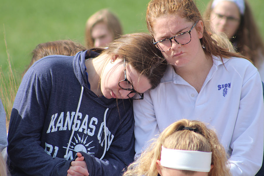 Senior Kate Sullivan leans on senior Aidan McEnerney’s shoulder as they sit in silence to mourn those who have died at the hands of gun violence.