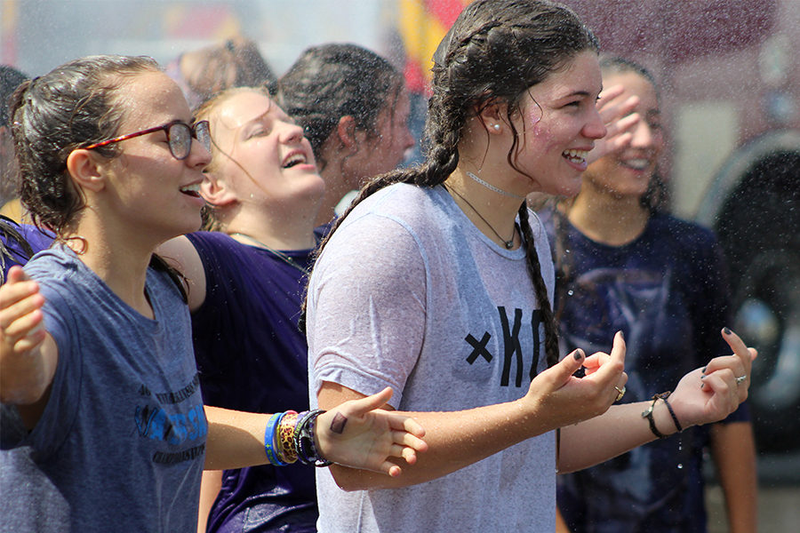 Seniors Kate Sullivan and Melissa Hamilton hold out their arms as they’re sprayed by the fire hose at Freshman Senior Field Day Aug. 25. The local fire department came at the end of the day while students enjoyed popsicles.