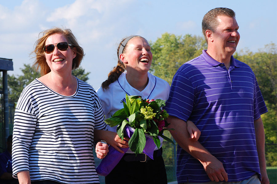 With flowers in hand, senior Sarah Schaffer laughs while her favorite memory is being read over the intercom at softball senior night Oct. 2. The storm lost the game against the Mid-Buchanan Dragons 12-18 and concluded the night with a dinner to honor the five seniors.