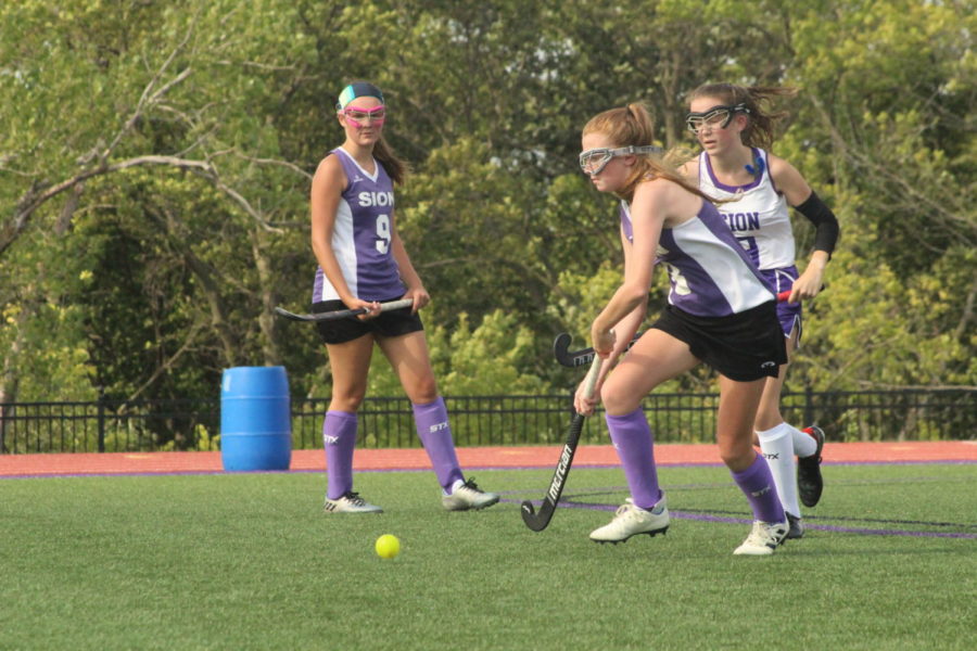 Freshman Grace Powers hits the ball away from junior Lilly Denney during the Purple and White field hockey scrimmage Aug. 28.