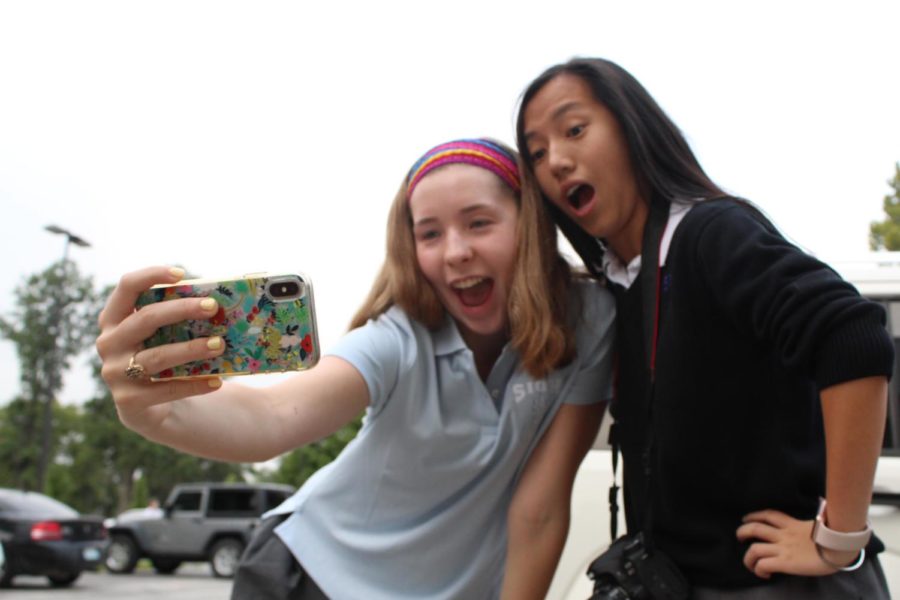 Seniors Emily Koca and Lilly Concannon pose for a selfie in the senior parking lot during the senior tailgate, Aug. 15. They plan to hang the selfie in their maison leader English teacher Melissa Wilcox’s room.