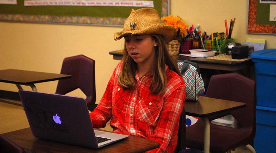 Dressed up as country music for spirit week, freshman Lydia Poe searches for volunteer opportunities on her laptop during Alive for All Life club  Sept. 19.