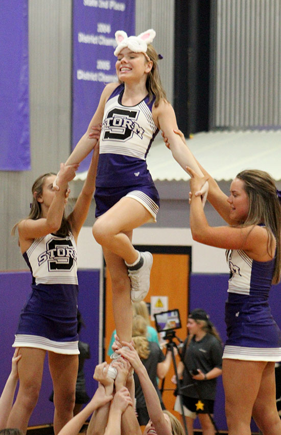 Sophomore Jane Oltjen stunts with the cheer team supported by sophomore Meg Wilkerson and senior Liz Oltjen at the volleyball game against St. Teresa’s Academy Sept. 12. STA won in two sets.