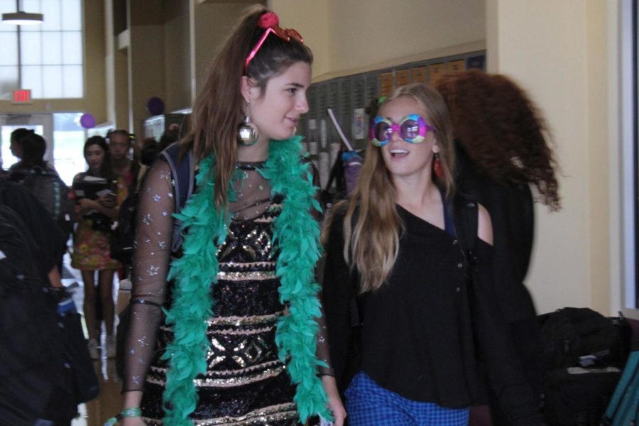 Dressed in disco outfits, juniors Reilly Jackoboice and Felicia Knox walk to class together on the music genre themed day Sept. 19. Freshmen were country, sophomores were Kidz Bob, juniors were disco, seniors were rock & roll and the faculty was 80’s.