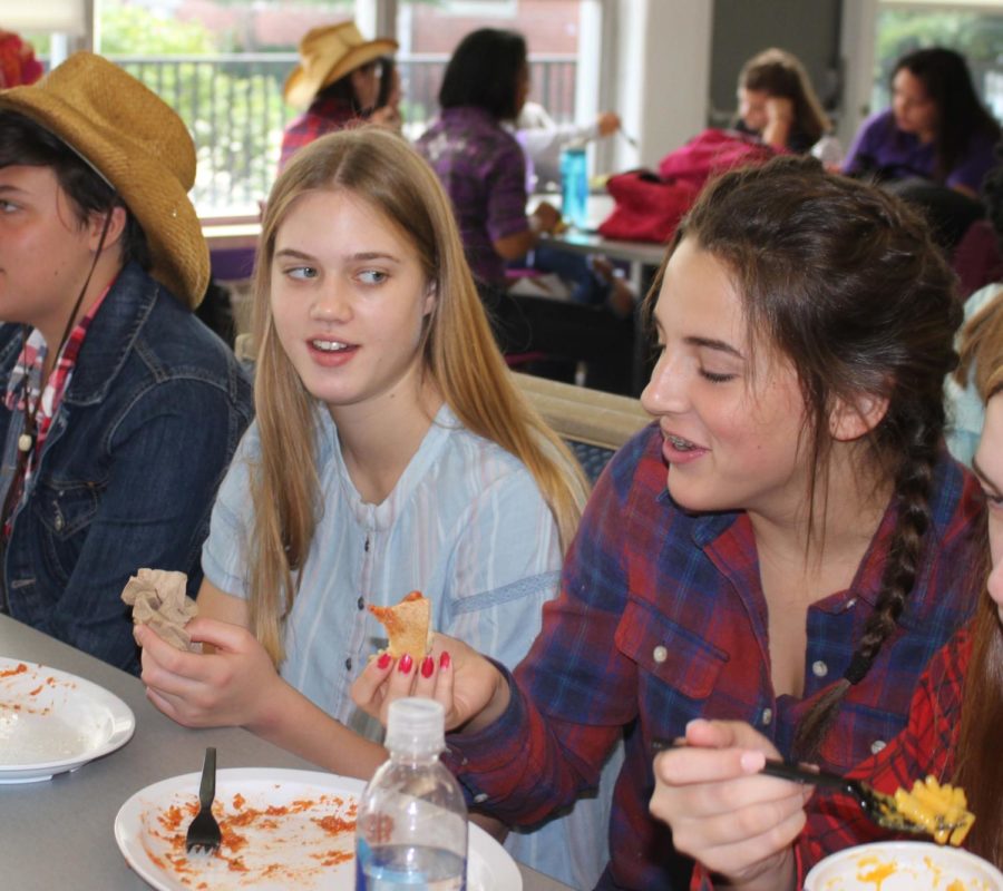 Freshman Julia Norman and Kate Accardo laugh at a joke told from across the table during lunch dressed as the freshman theme of country on music genre day of spirit week Sept. 19. 