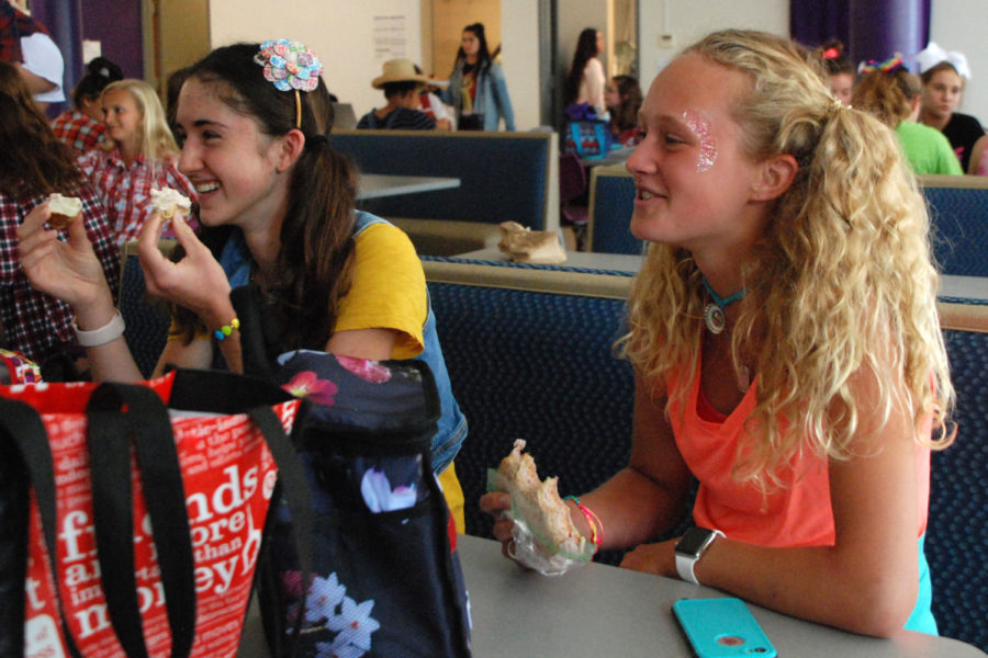 Sophomores Olivia Overlease and Grace Hill laugh while enjoying their lunch with their friends during spirit week in their Kidz Bop attire Sept. 19. The theme for the day was musical genres.