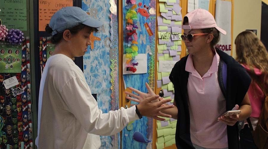 Sophomores Morgan Herriott and Catherine Crayon clap hands in the freshman hallway during spirit week last year dressed for the Yacht Club theme.