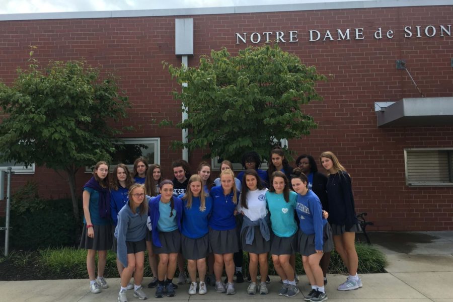 The Le Journal staff wearing their blue shirts in front of the high school.