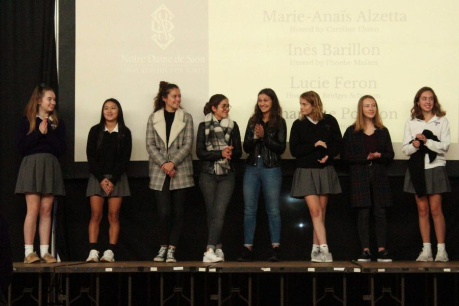 French Exchange students stand with their host sisters up on stage during the first quarter Grande Assemblee.