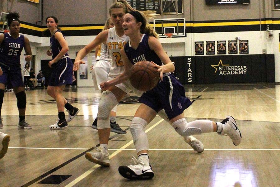 Junior Lily Henkle runs around STA defender Lily Farkiss in an attempt to shoot on goal, moments before being fouled Dec. 4.