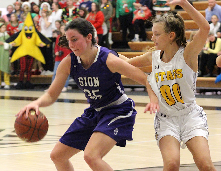 Sophomore Shannon Karlin goes in for a lay up while being guarded by Saint Teresa’s Academy junior Grace Kauten during the basketball game versus STA at STA Dec. 4. STA won 43-40 after a close finish. 