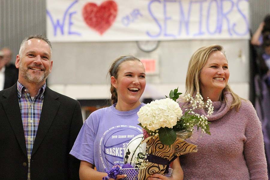 Senior Mia McLey stands with her parents Mike and Catherine to be recognized at the senior ceremony before the basketball game Feb. 21. McLey was recognized with fellow senior players Gretta Allen, Molly Wagner and Vanshay Purnell and senior manager Kaitlin Jones. 