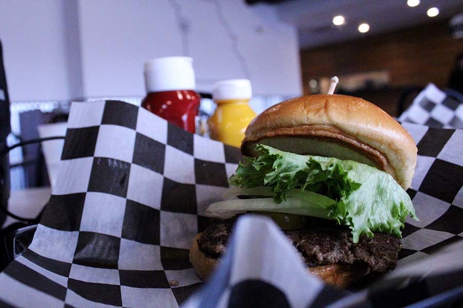 As single State burger is served on black and white plaid paper at Burger State. 