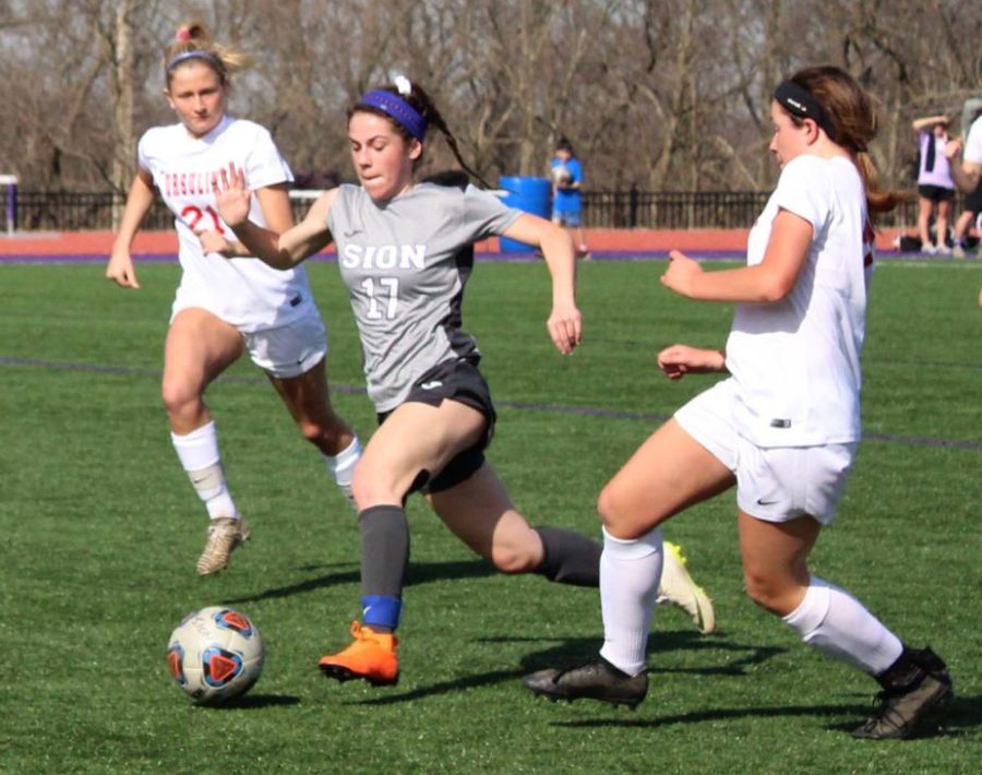 During the first home game against Ursuline Academy March 22, sophomore Kennedy Ruark dribbles through two defensive players, to make a shot on goal. The team won with a score of 3-1.