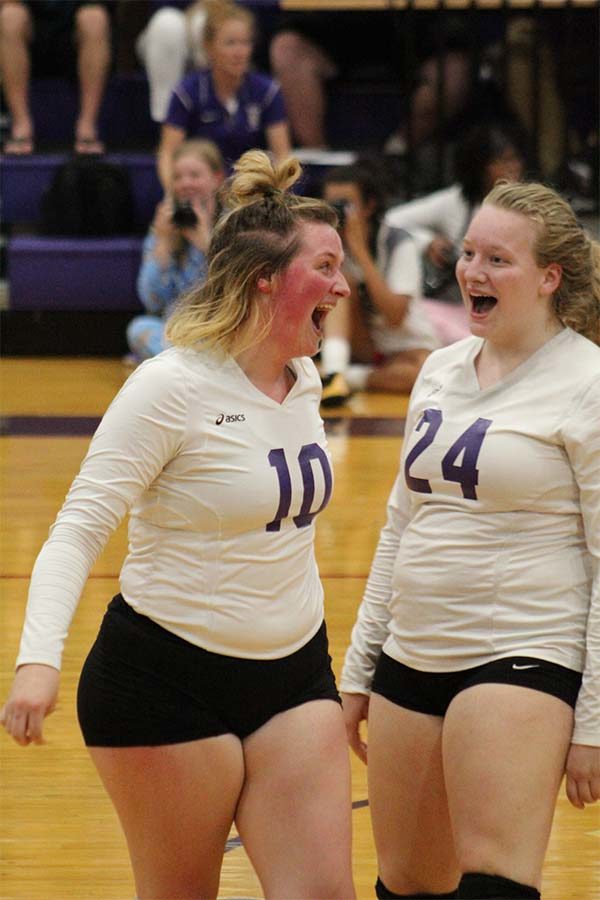 Seniors Caroline Garrison and Savannah Friedebach cheer after the Storm wins the point against St. Teresa’s Academy volleyball team Sept. 12. The team lost in two games.