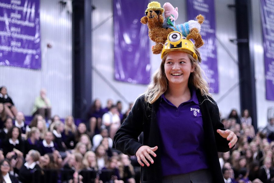 Walking away after recieving her beanie, freshman Brynna Fitzgerald shows off to her classmates in the gym during the beanie ceremony on Aug. 22.