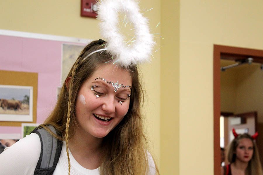 dressed in white clothing with a furry halo for Spirit Week theme Devils and Angels, Senior Maddy Anstoetter talks with classmates before her second-hour class Sept 11. 