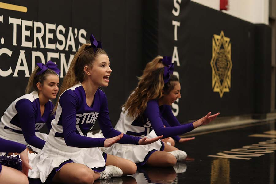 Senior Rachel McRae and juniors Bella Aquino and Sophia Allen perform a cheer during the varsity basketball game against St. Teresa's Academy at STA Dec. 6.