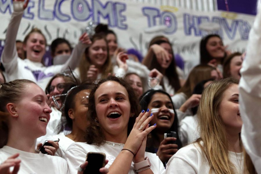 Juniors Sophie Henkle and Caroline Giocondo laugh as they cheer on the varsity basketball team during their game against St. Teresa's Academy Feb. 27. 