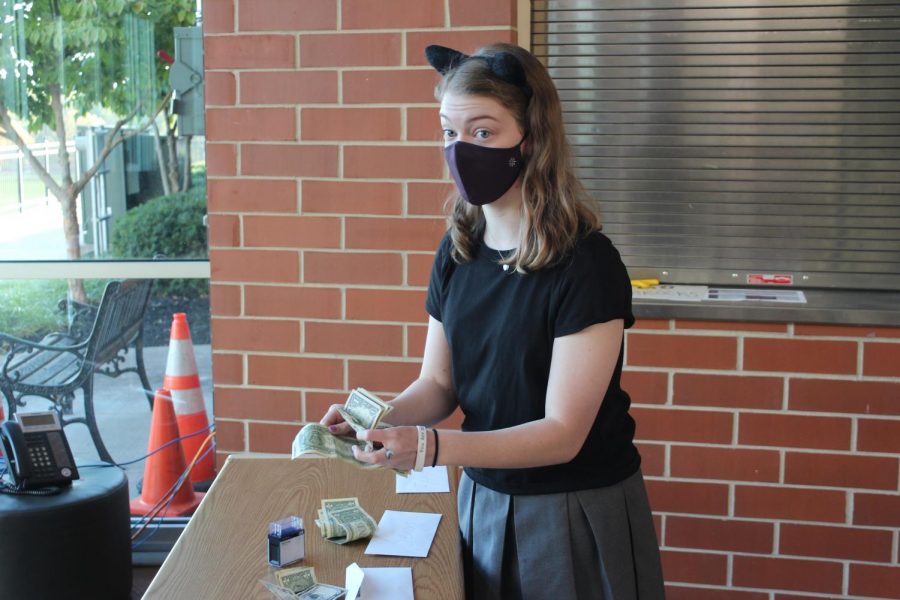 Junior Tess Tappan counted and collected money at the gym entrance as students paid to wear their costumes Oct. 30.