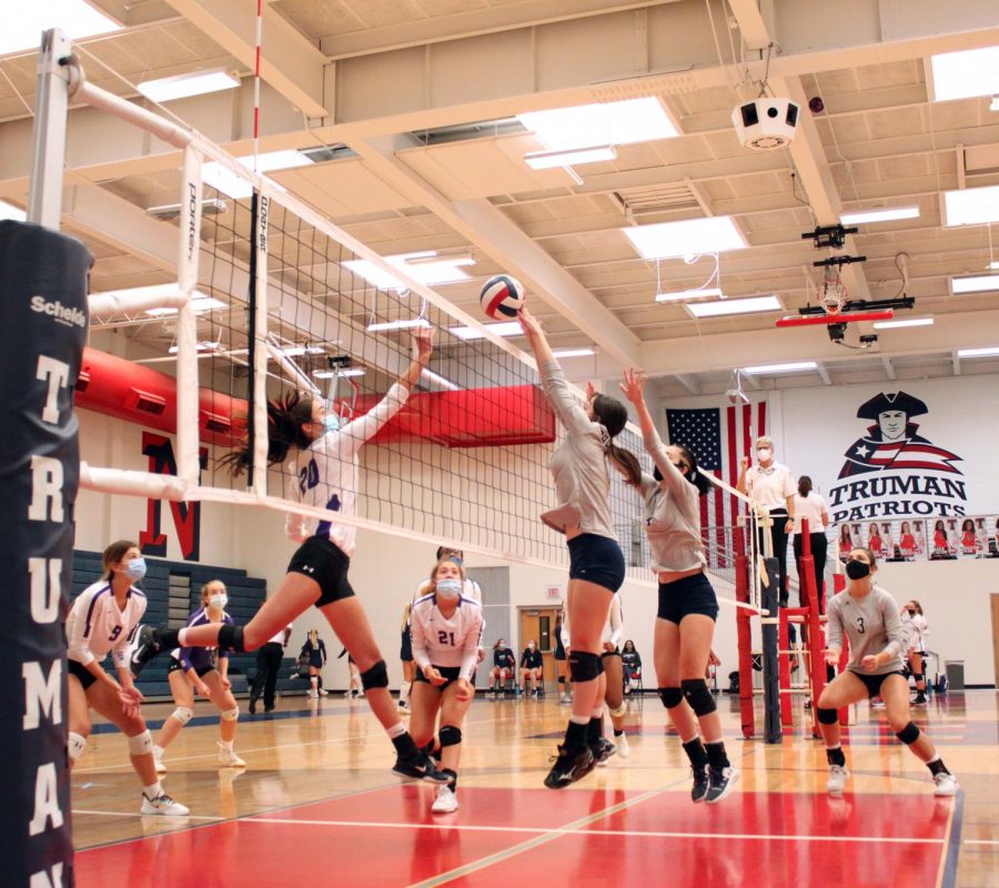 Junior Anna Sheedy jumps to block the volleyball as a student from William Chrisman High School sets it over the net. 