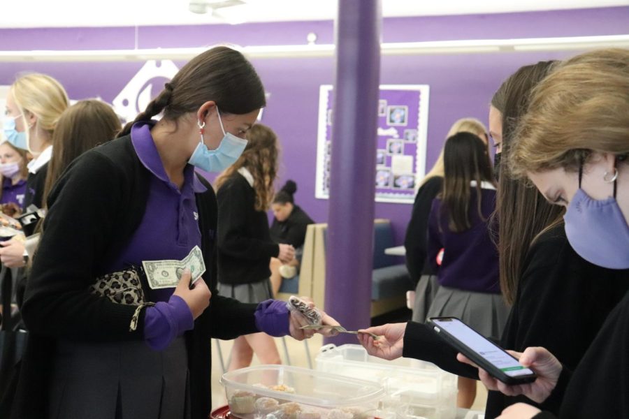 Junior Isabel Dumsky buys a brownie at the Lemon Club bake sale during her lunch period.