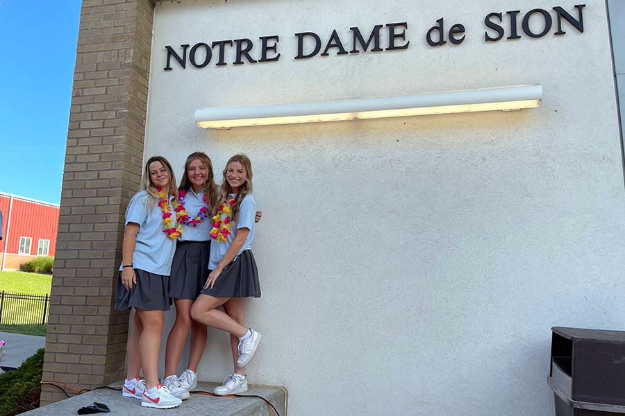 Seniors Maddie Haukap, Taylor Crouch, and Kate McCarthy pose for a signature photo at the gym entrance during the senior tailgate.