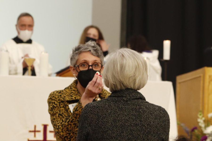 Principal of Academics Ellen Carmody gives communion to a guest.