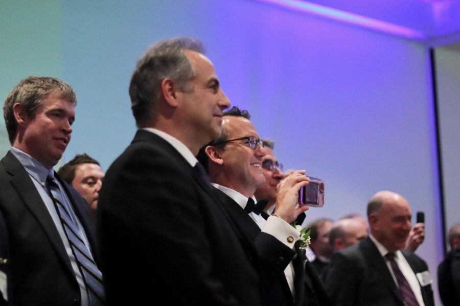 Dads of seniors watch their daughters sing on the dance floor. 