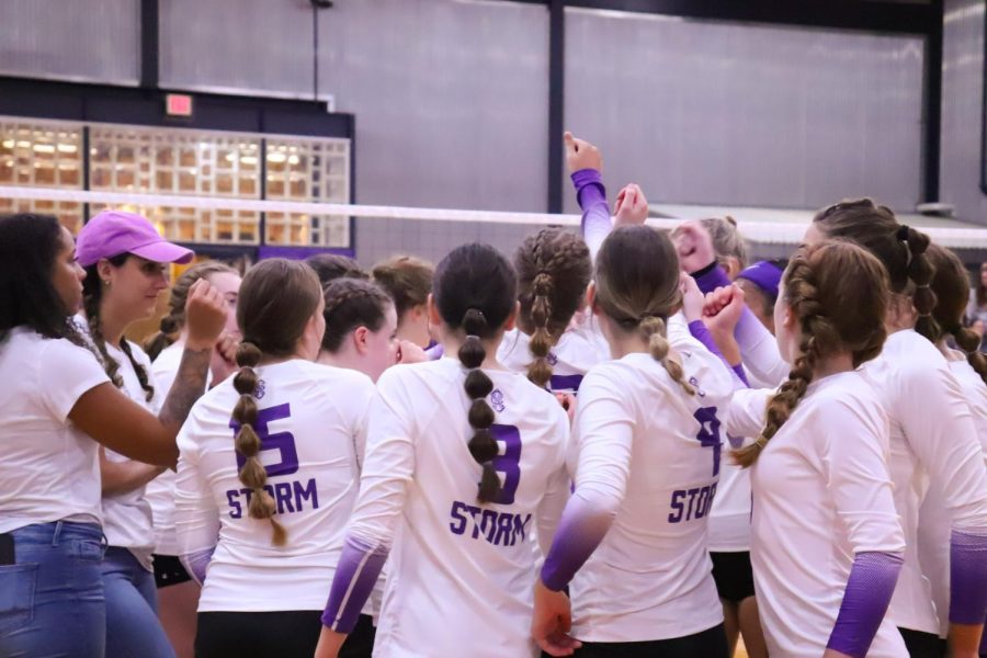 The volleyball team gathers for a huddle during a timeout. 