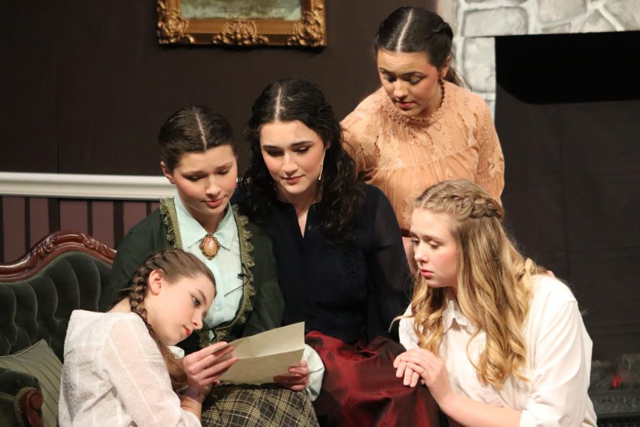 The four March sisters, played by seniors Addie Hiestand and Carolina O'Byrne, junior Noelle Bertrand and freshman Arle McCallon, and Marmee, played by junior Suzanne Sade, gather around the couch to read a letter. 