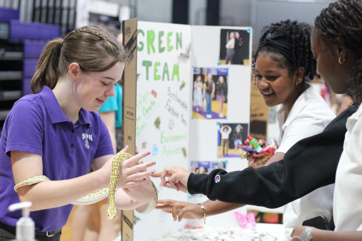 Smiling, junior Heidi Nance holds a snake in front of two potential club members Aug. 21. Nance is the co-president of Sion's Green Team alongside senior Becca Houlehan and junior Summer Bannigan.